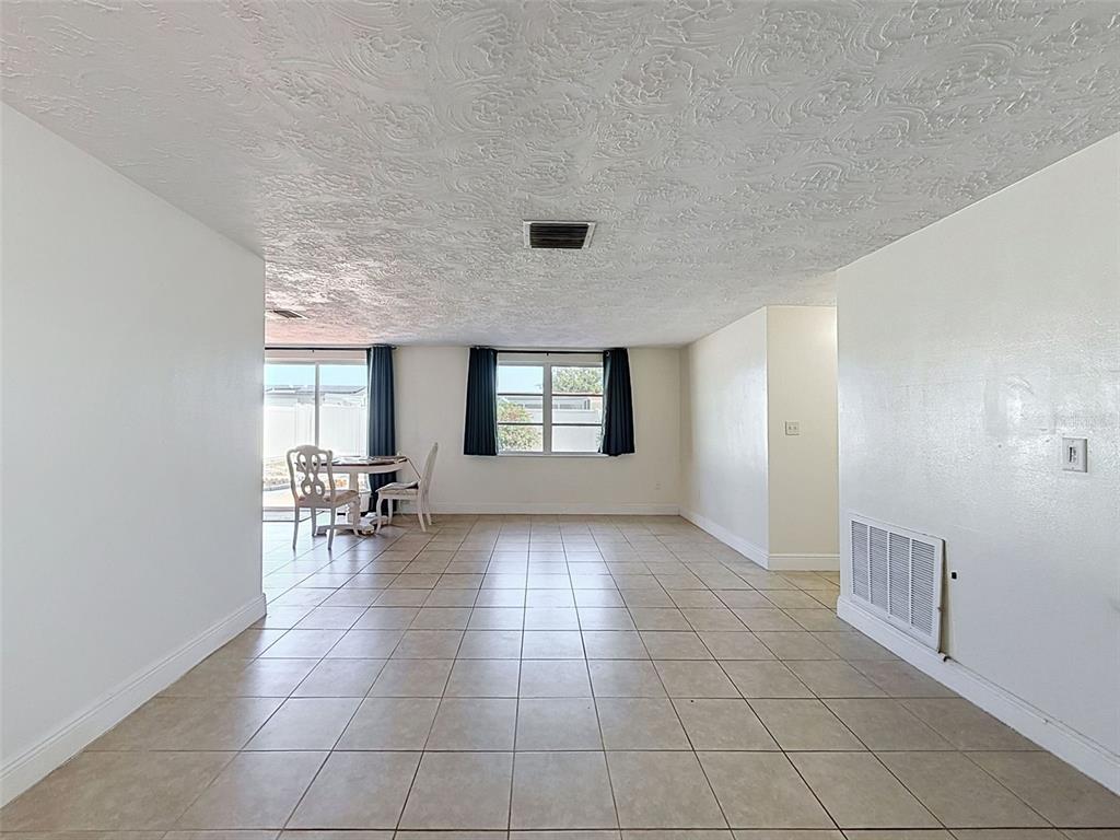 An empty room with beige tile flooring, white walls, and a textured ceiling — 3345 CHAUNCY ROAD, HOLIDAY, FL