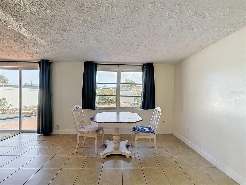 A dining area features a table with two chairs, tile flooring, and a textured ceiling — 3345 CHAUNCY ROAD, HOLIDAY, FL