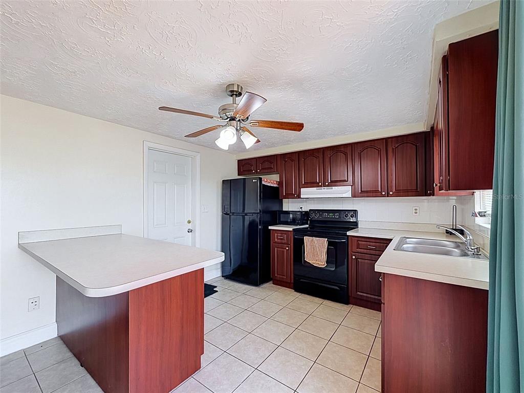 A kitchen features dark wood cabinets, black appliances, a tiled floor, and a breakfast bar — 3345 CHAUNCY ROAD, HOLIDAY, FL