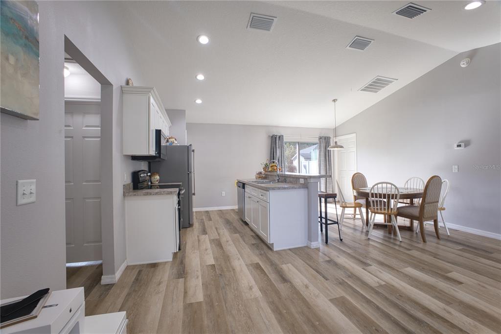 A kitchen with white cabinets and a dining area with a table and chairs — 3144 SE 144TH PLACE, SUMMERFIELD, FL