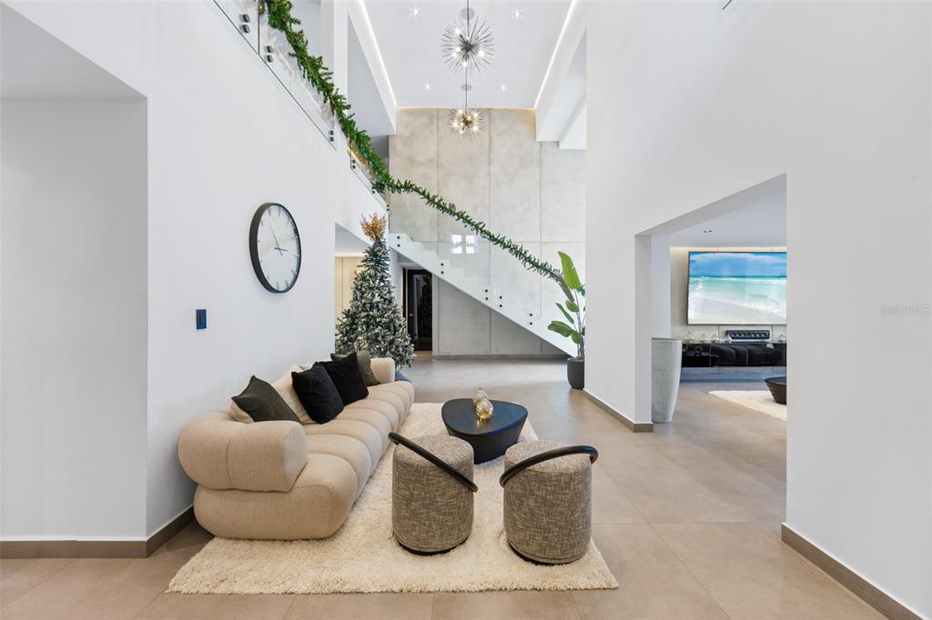 A modern living room features a beige sofa, two ottomans, and a staircase with greenery — NN1 CALLE NACAR, DORADO DEL MAR, DORADO, PR