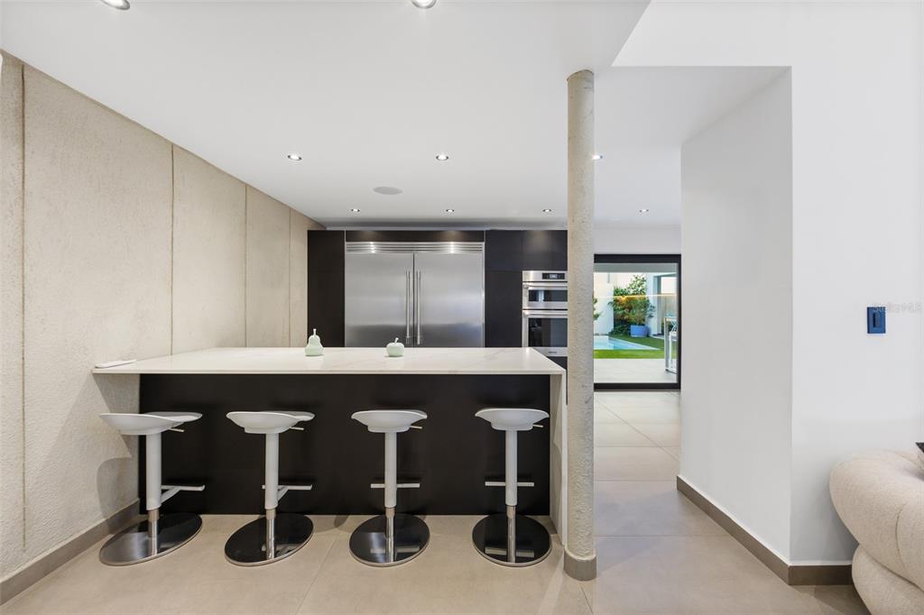 A modern kitchen features a white island with four bar stools and stainless steel appliances — NN1 CALLE NACAR, DORADO DEL MAR, DORADO, PR