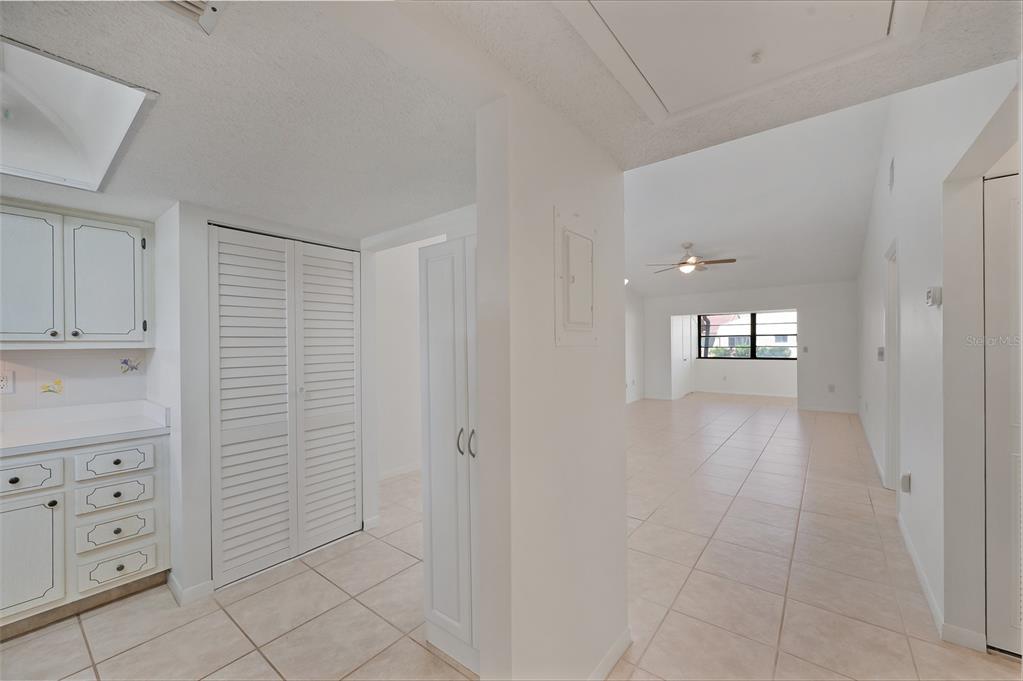 A white kitchen with louvered closet doors opens into a tiled living area — 1407 58TH STREET W UNIT 1407, BRADENTON, FL