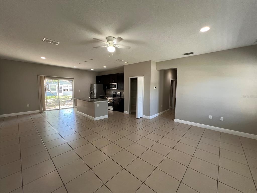 An open-concept living area features tile flooring, a kitchen with dark cabinets, and sliding doors — 528 FINCH LANE, KISSIMMEE, FL
