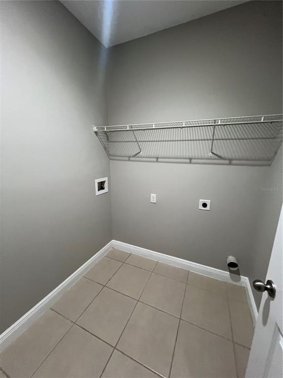 A laundry room with gray walls, tile flooring, and a white wire shelf — 528 FINCH LANE, KISSIMMEE, FL