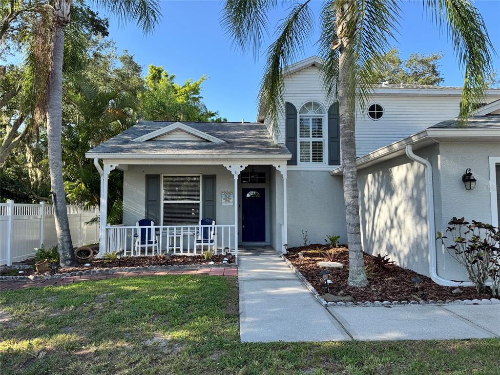 A two-story house with a front porch, blue door, and palm trees in the yard — 11302 3RD AVENUE E, BRADENTON, FL