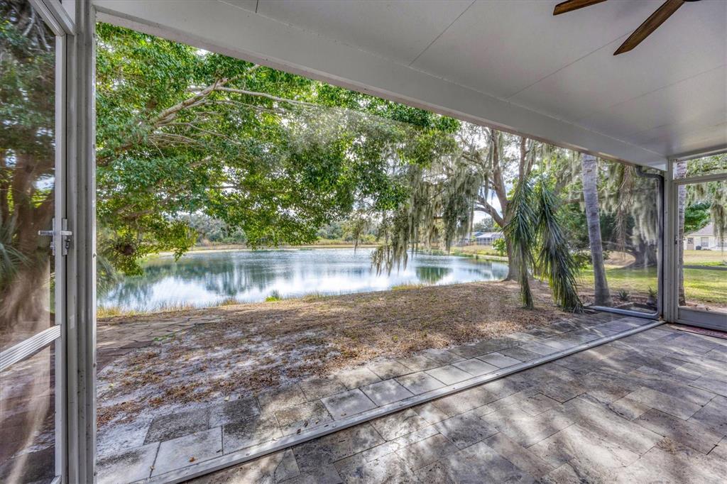A screened-in patio with stone flooring overlooks a pond surrounded by trees — 11302 3RD AVENUE E, BRADENTON, FL