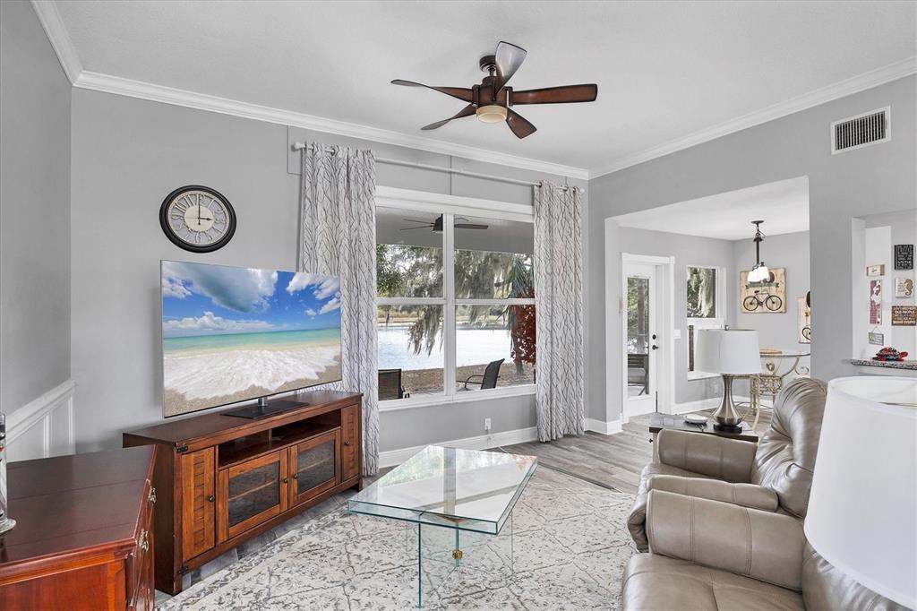 A living room with a television, glass coffee table, leather recliner, and a lake view — 11302 3RD AVENUE E, BRADENTON, FL