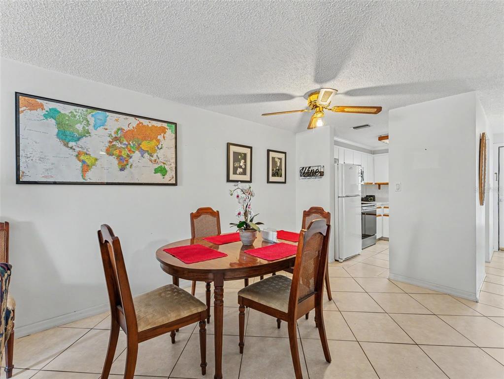 A dining area with a wooden table, four chairs, and a world map on the wall — 6340 E PROVIDENCE CIRCLE UNIT 204, NEW PORT RICHEY, FL