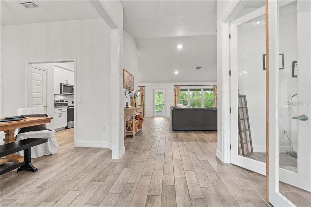 A bright open-concept living area features light wood-look tile flooring and a white kitchen — 5436 JESSAMINE AVENUE, NORTH PORT, FL