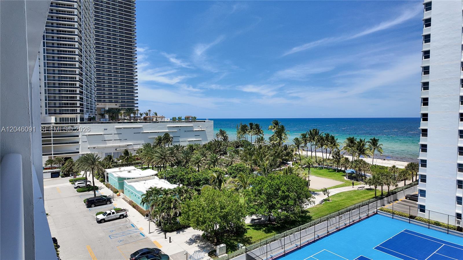 An elevated view shows a parking lot, palm trees, a tennis court, and the ocean — 1880 S Ocean Dr # 807, Hallandale Beach FL 33009, HALLANDALE BEACH, FL