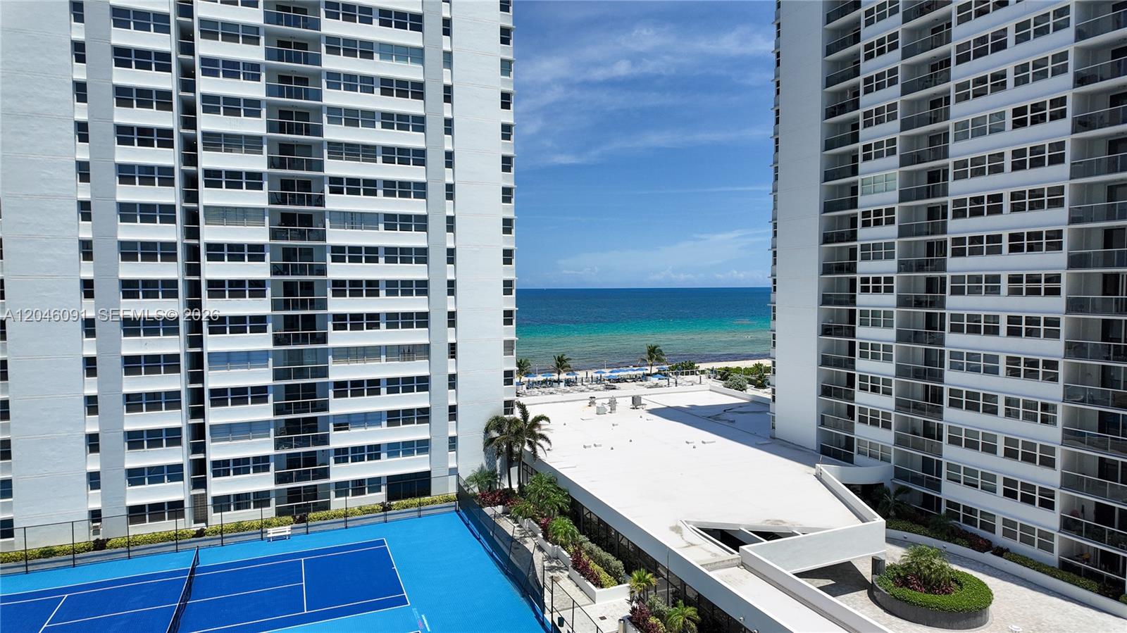 An elevated view shows a blue tennis court between two tall residential apartment buildings — 1880 S Ocean Dr # 807, Hallandale Beach FL 33009, HALLANDALE BEACH, FL