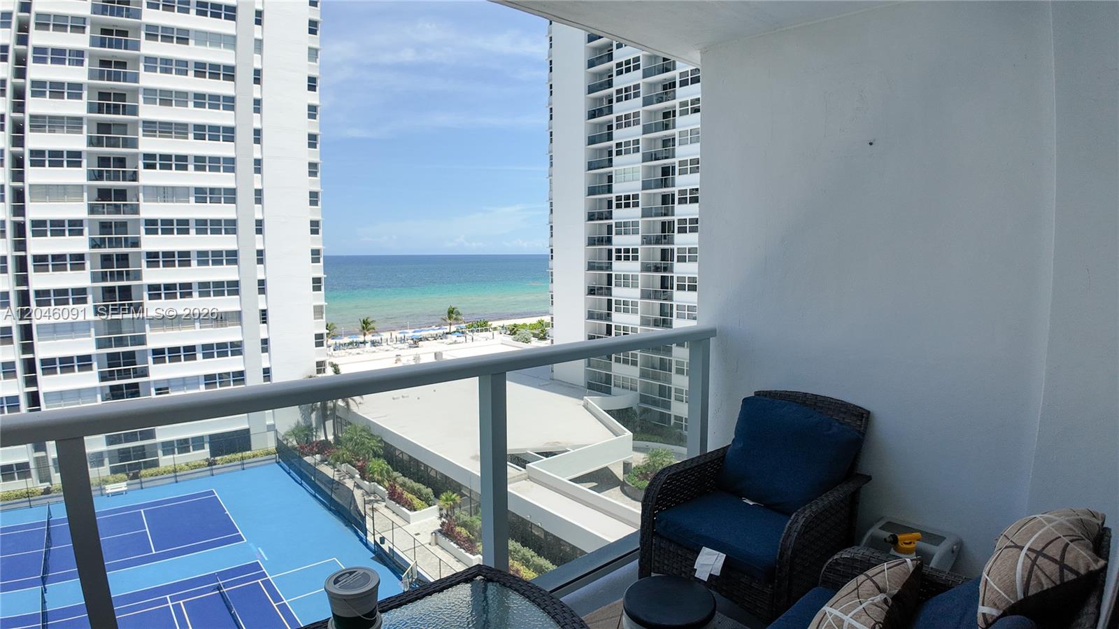 A balcony overlooks a tennis court, a beach, and the ocean between two high-rise buildings — 1880 S Ocean Dr # 807, Hallandale Beach FL 33009, HALLANDALE BEACH, FL