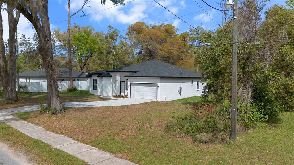 A white single-story house with a dark roof and a two-car garage sits on grass — 1221 SW 5TH STREET, OCALA, FL
