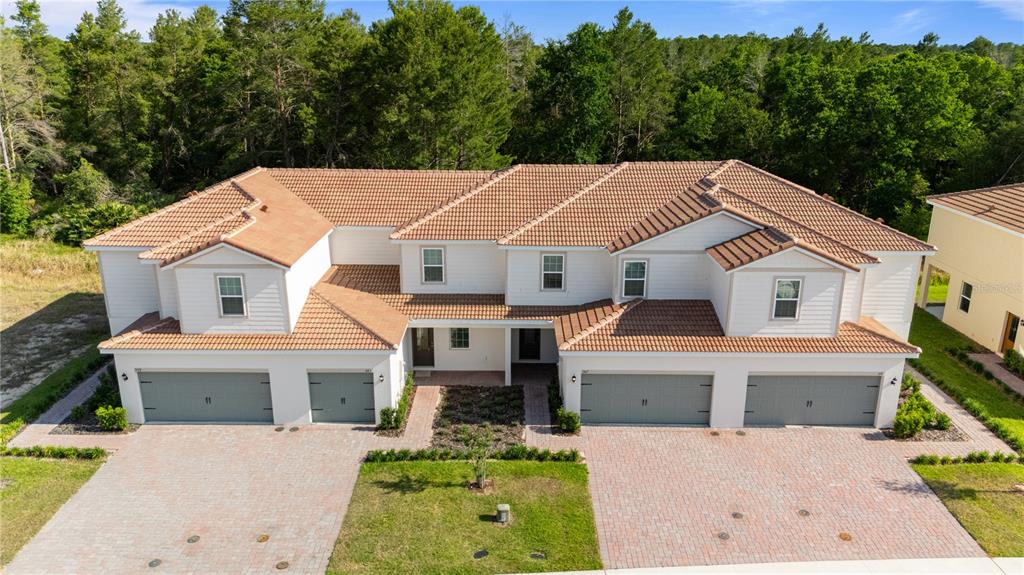 An aerial view of a two-story duplex with a tiled roof and brick paver driveways — 567 BAY LEAF DRIVE, KISSIMMEE, FL