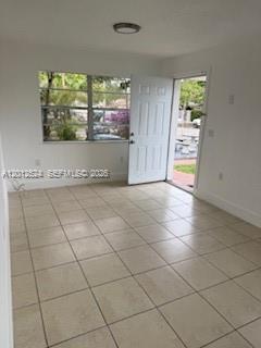 A bright room with white walls, light-colored tile flooring, a window, and an open door — 1074 NW 27th St # 0, Miami FL 33127, MIAMI, FL