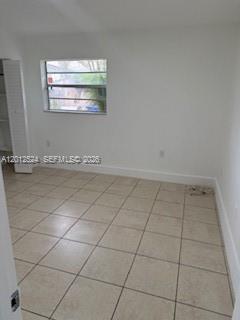 An empty bedroom features white walls, beige tile flooring, and a single window — 1074 NW 27th St # 0, Miami FL 33127, MIAMI, FL