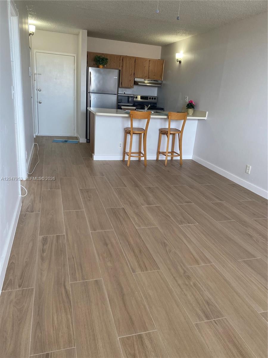 A kitchen with wood cabinets and a breakfast bar overlooks an open living area — CORAL SPRINGS, FL