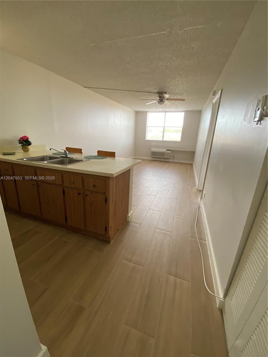 A kitchen with a breakfast bar and light-colored tile flooring opens into a living area — CORAL SPRINGS, FL