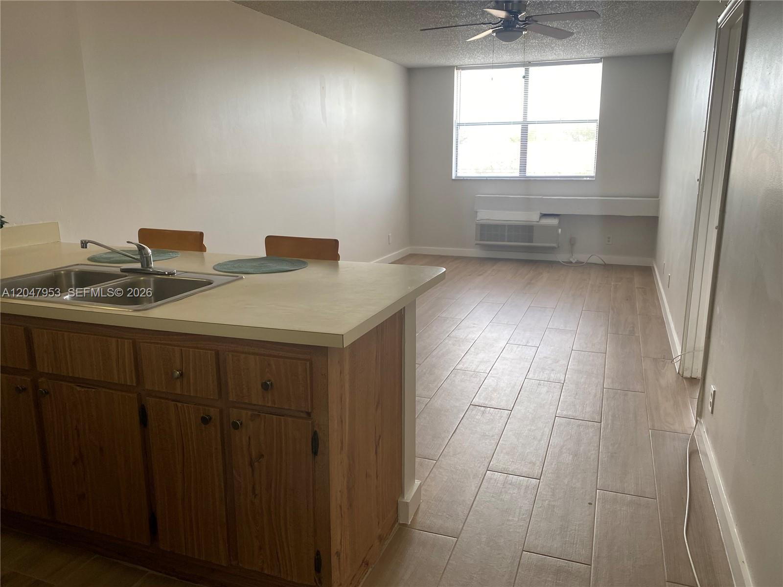 A kitchen island with a sink overlooks an open living area with tile flooring — CORAL SPRINGS, FL