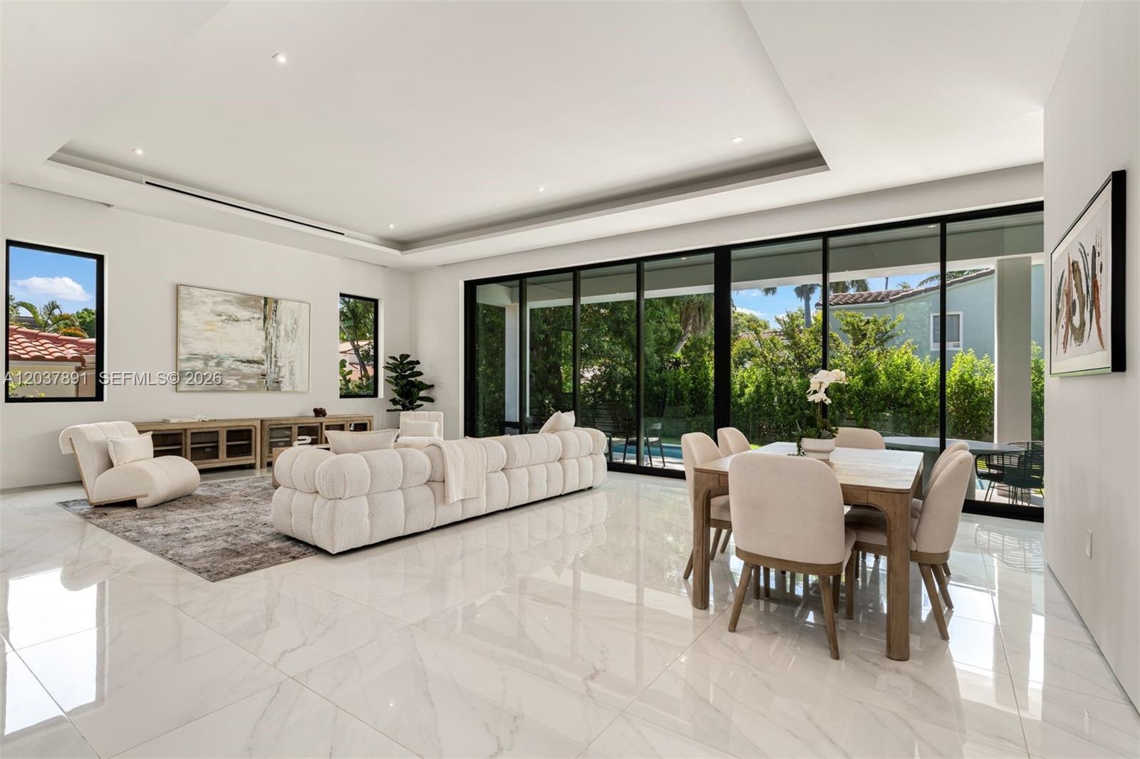 A bright, open-concept living and dining area features white marble floors and large glass doors — 4430 Nautilus Dr, Miami Beach FL 33140, MIAMI BEACH, FL