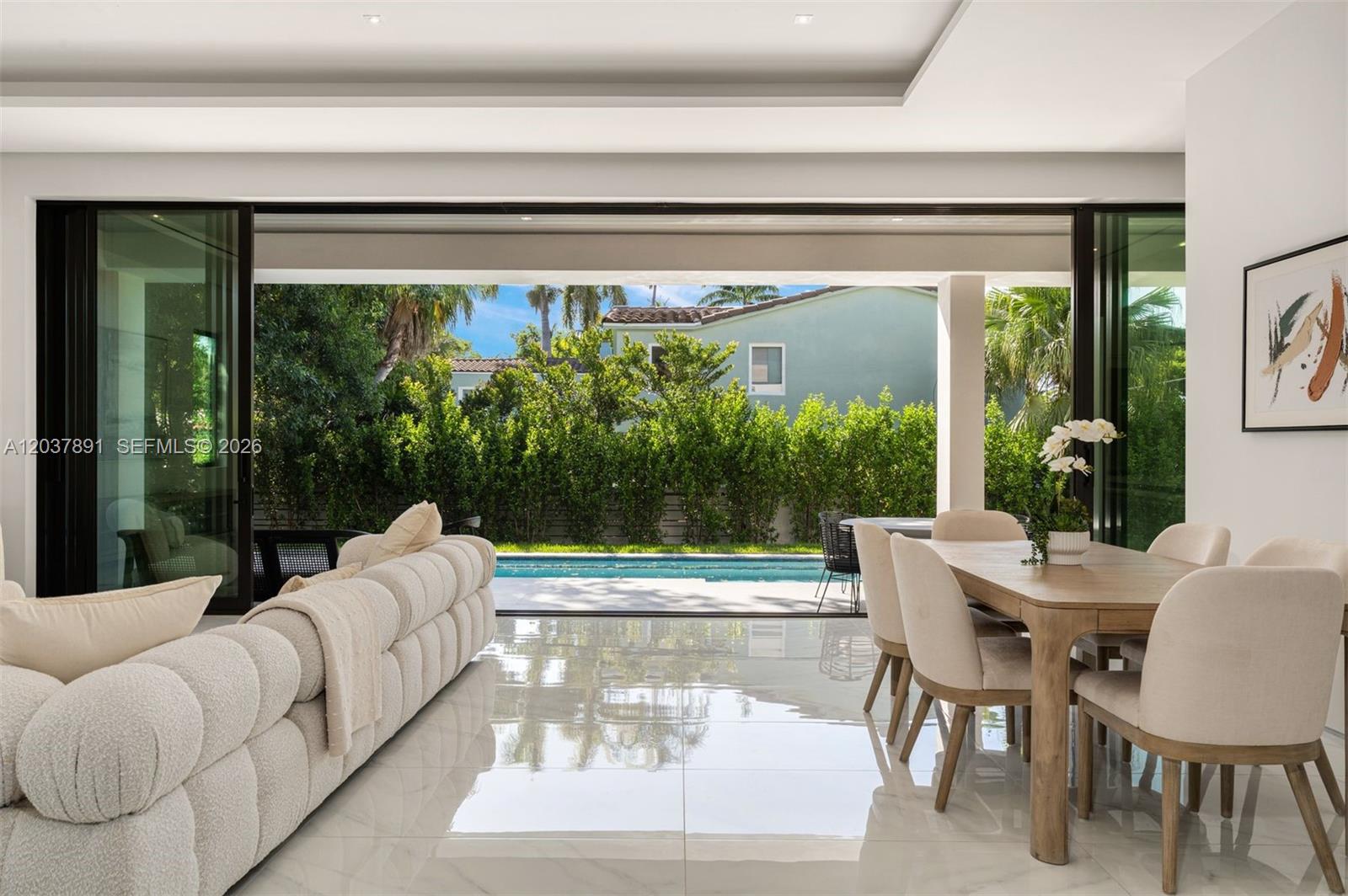 A modern living and dining area opens to a patio with a swimming pool — 4430 Nautilus Dr, Miami Beach FL 33140, MIAMI BEACH, FL