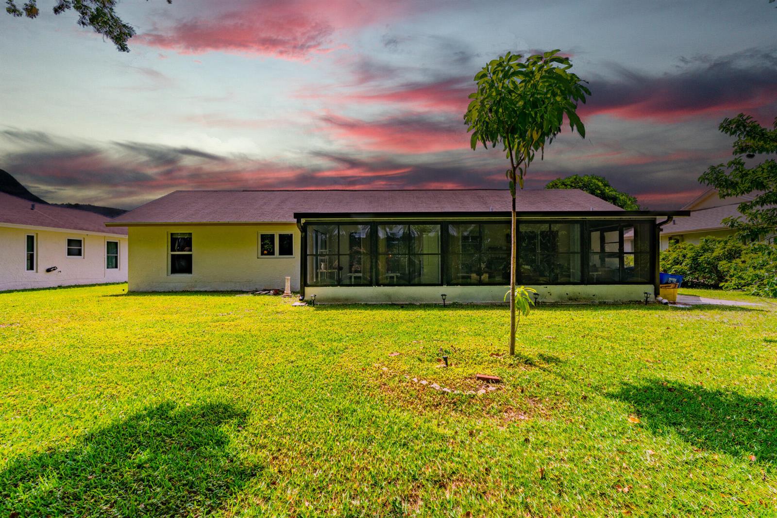 The backyard of a single-story house features a screened-in porch and a small tree — 14759 Hideaway Lane, Delray Beach FL 33484, DELRAY BEACH, FL