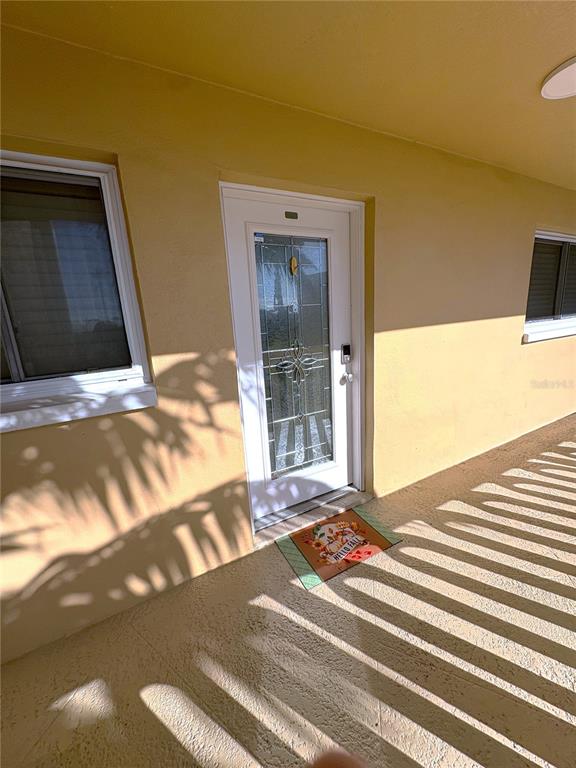 A yellow exterior wall features a white front door with glass panels and two windows — 11605 3RD STREET E UNIT 306, TREASURE ISLAND, FL