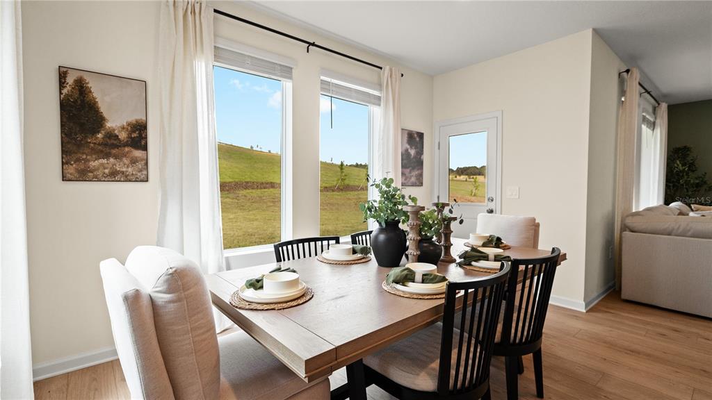 A dining room features a wooden table, chairs, large windows, and a view of hills — 1921 FIELDSTONE STREET, MINNEOLA, FL