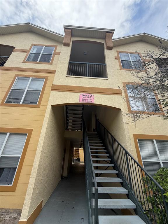 A low-angle exterior view of a three-story apartment building with an outdoor staircase — 5612 PINNACLE HEIGHTS CIRCLE UNIT 302, TAMPA, FL