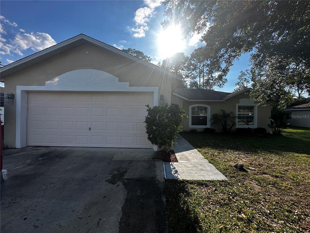 A single-story house with a beige exterior, a two-car garage, and a concrete walkway — 18 RED CLOVER LANE, PALM COAST, FL