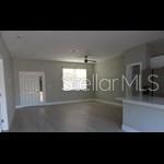 An open-concept living area features light-colored flooring, gray walls, and a kitchen island — 179 FISHER WAY TRAIL, OCKLAWAHA, FL
