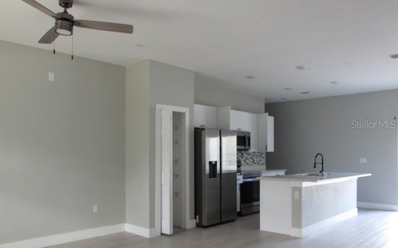 A modern kitchen features white cabinets, stainless steel appliances, and a central island with seating — 179 FISHER WAY TRAIL, OCKLAWAHA, FL