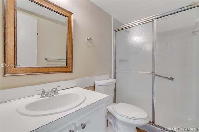 A bathroom featuring a vanity with a mirror, a toilet, and a glass-enclosed shower — 4759 Sable Pine Circle # A2, West Palm Beach FL 33417, WEST PALM BEACH, FL