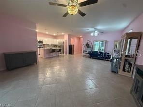 An open-concept living area features light pink walls, tile flooring, and a kitchen with white cabinets — 1881 W ISLES ROAD, PORT CHARLOTTE, FL