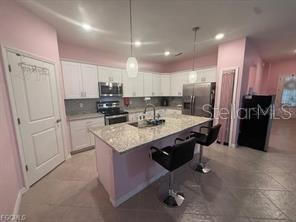A kitchen with white cabinets, granite countertops, a center island with stools, and stainless appliances — 1881 W ISLES ROAD, PORT CHARLOTTE, FL