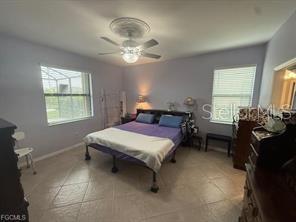 A bedroom features a bed with a purple cover, a ceiling fan, and tiled floors — 1881 W ISLES ROAD, PORT CHARLOTTE, FL