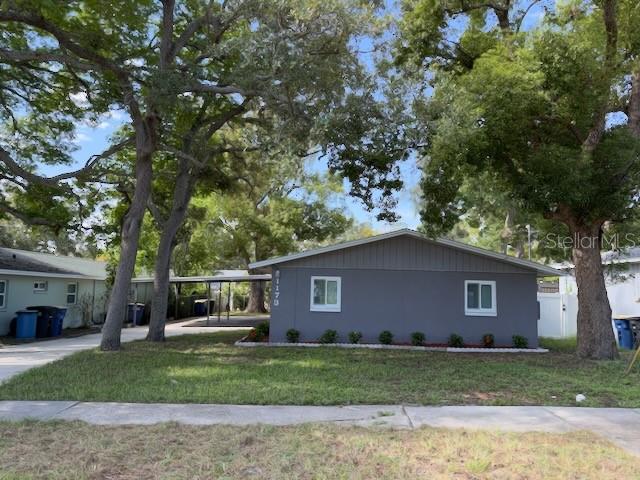 A single-story gray house with a carport and mature trees in the front yard — 1173 GRANADA STREET, CLEARWATER, FL