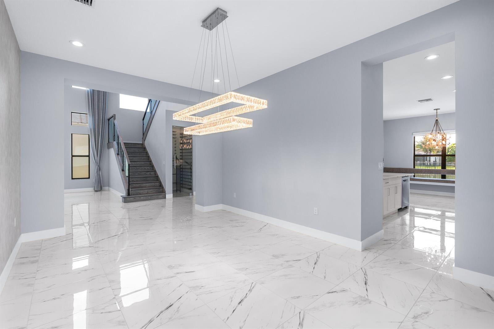 A dining room features a rectangular table, upholstered chairs, a crystal chandelier, and marble flooring — 17411 Sea Blossom Way, Boca Raton FL 33496, BOCA RATON, FL