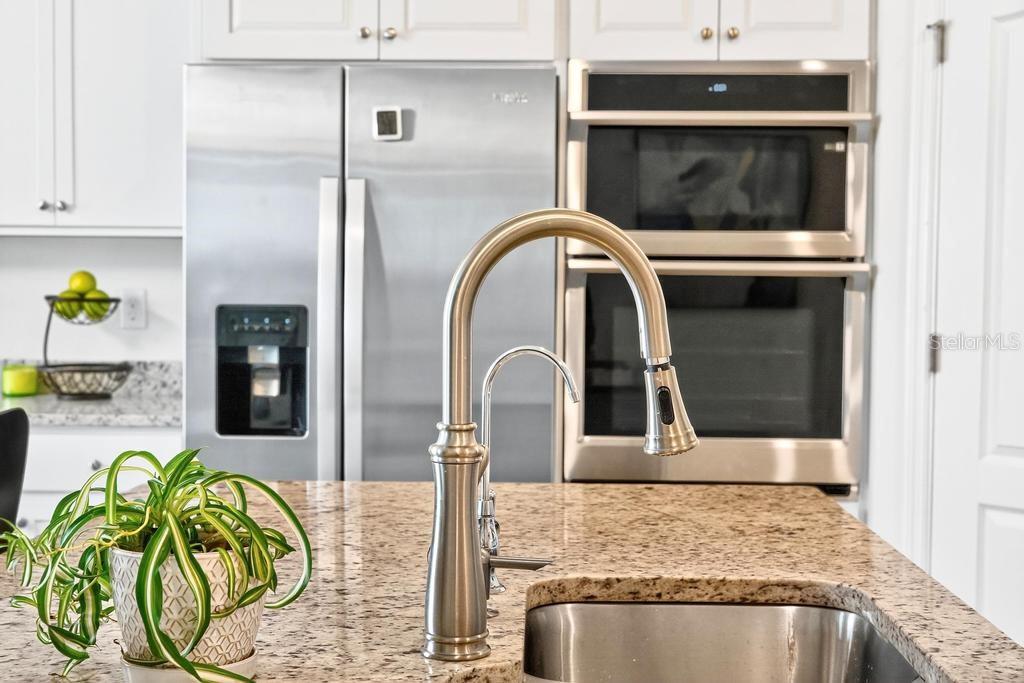 A kitchen island features a stainless steel faucet and sink in front of stainless steel appliances — 33470 ALWAYS DREAMING COURT, SORRENTO, FL