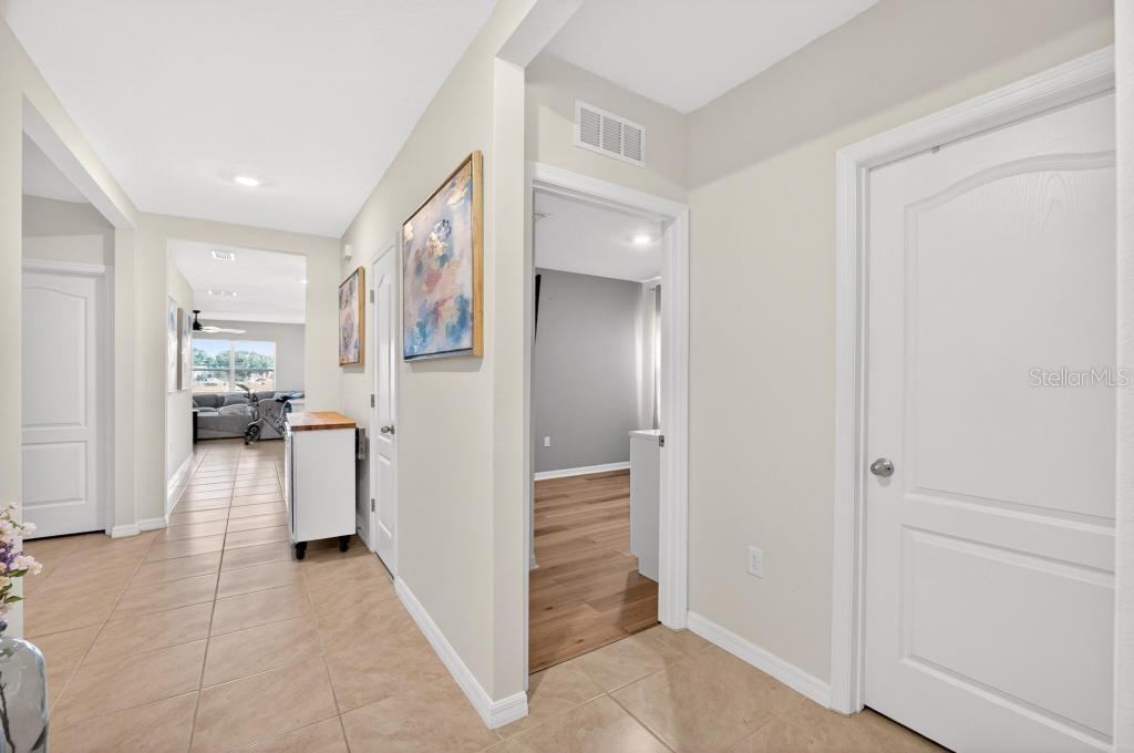 A hallway with tile flooring leads to an open living area with wood-look floors — 33470 ALWAYS DREAMING COURT, SORRENTO, FL