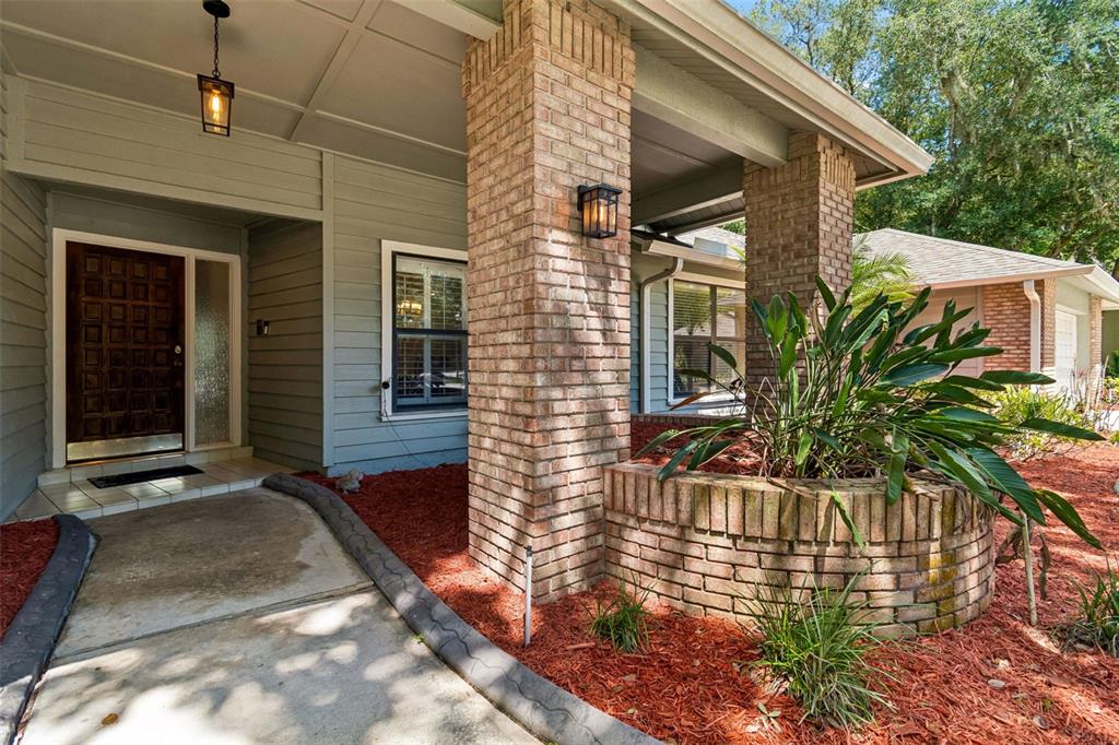 The exterior of a house features a brick pillar, a front door, and a planter — 5804 AINSWORTH COURT E, TAMPA, FL