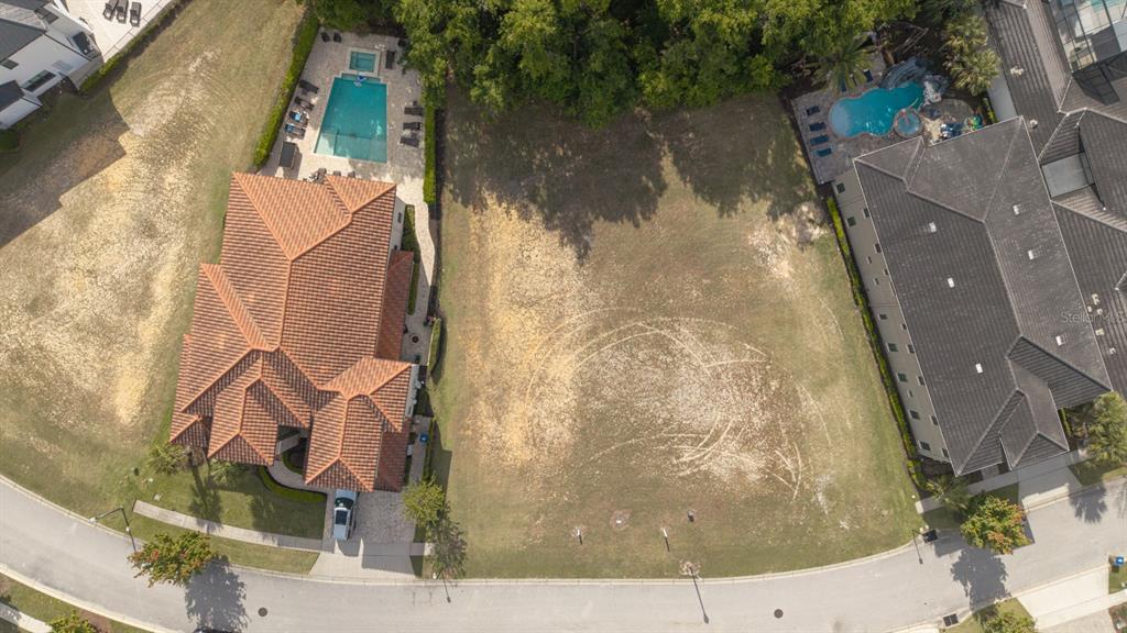 An aerial view shows a vacant residential lot situated between two houses with swimming pools — 8188 VALHALLA TERRACE, REUNION, FL