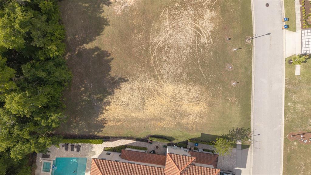 An aerial view shows a vacant, grassy residential lot adjacent to a house with a pool — 8188 VALHALLA TERRACE, REUNION, FL