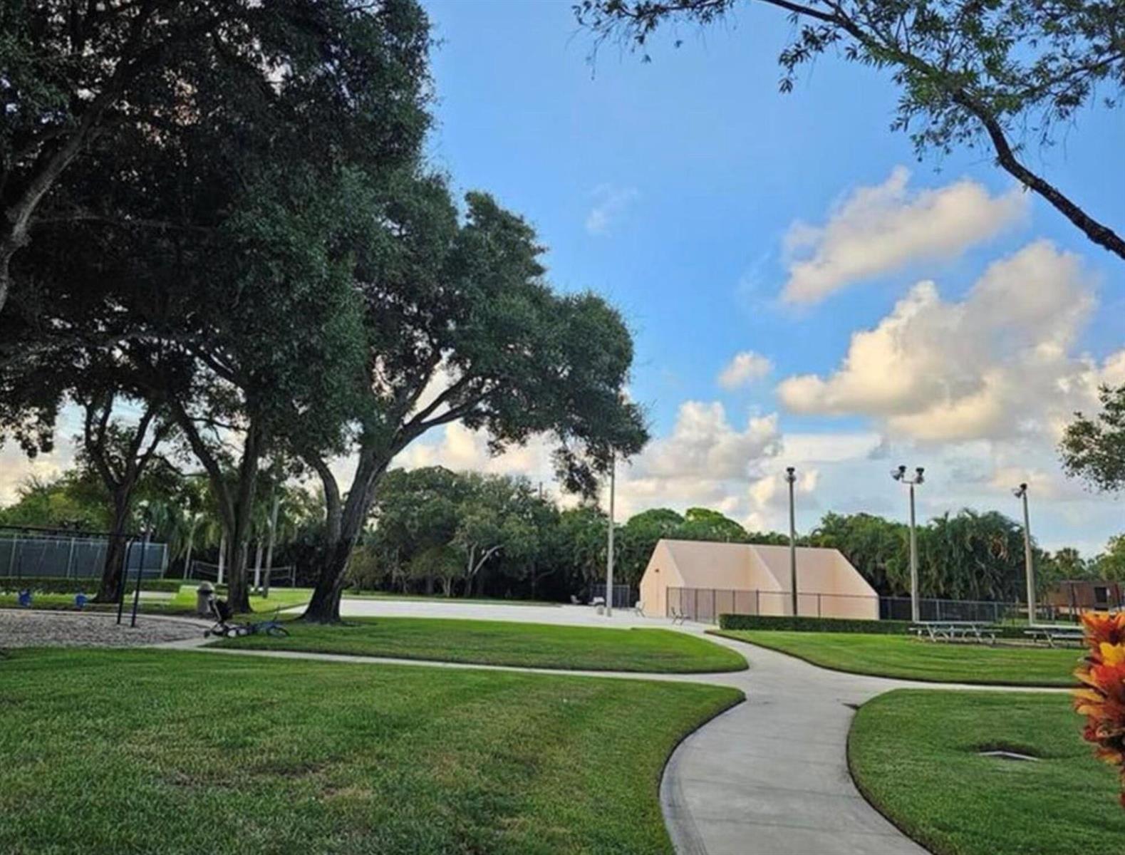 A paved path winds through a grassy park with large trees and a small building — 197 Charter Way, West Palm Beach FL 33407, WEST PALM BEACH, FL