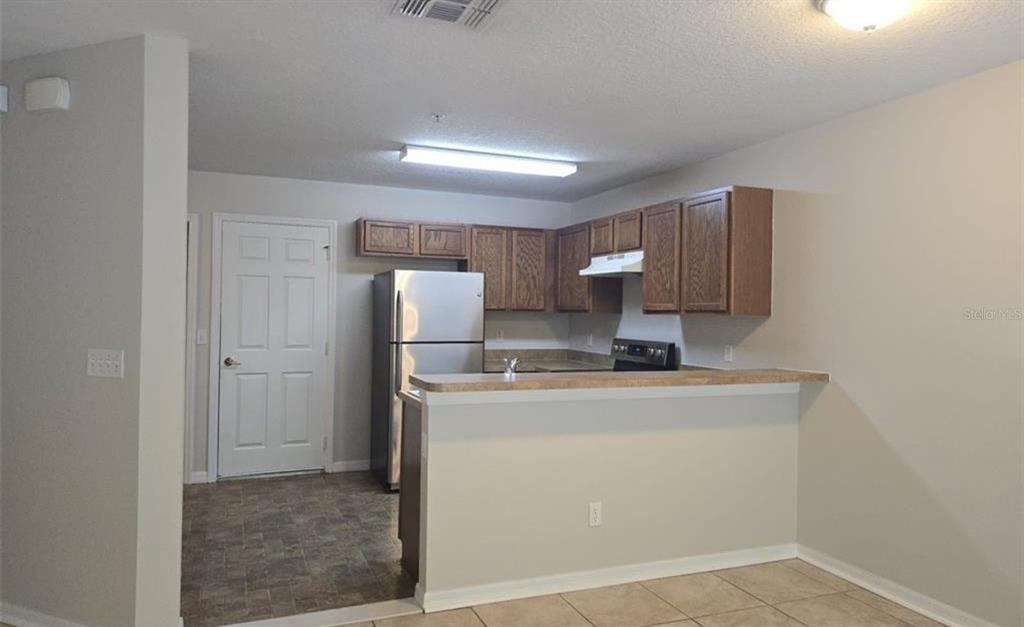 A kitchen with wood cabinets, stainless steel appliances, and a breakfast bar counter — 219 GLOWING PEACE LN UNIT 85, ORLANDO, FL