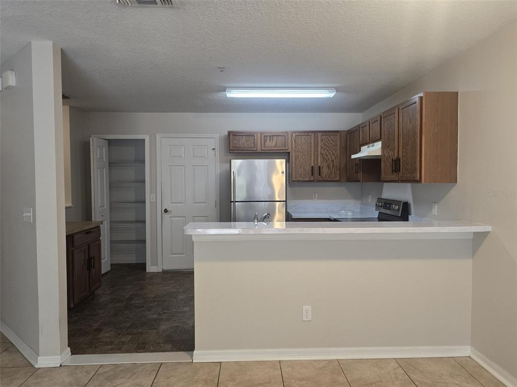 A kitchen features wood cabinets, stainless steel appliances, a breakfast bar, and a pantry closet — 219 GLOWING PEACE LN UNIT 85, ORLANDO, FL