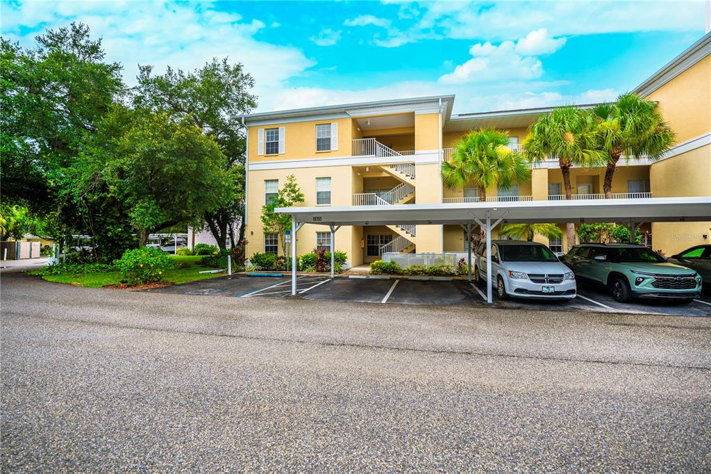 A three-story apartment building with a covered parking area and two parked cars — 19355 WATER OAK DRIVE UNIT 101, PORT CHARLOTTE, FL