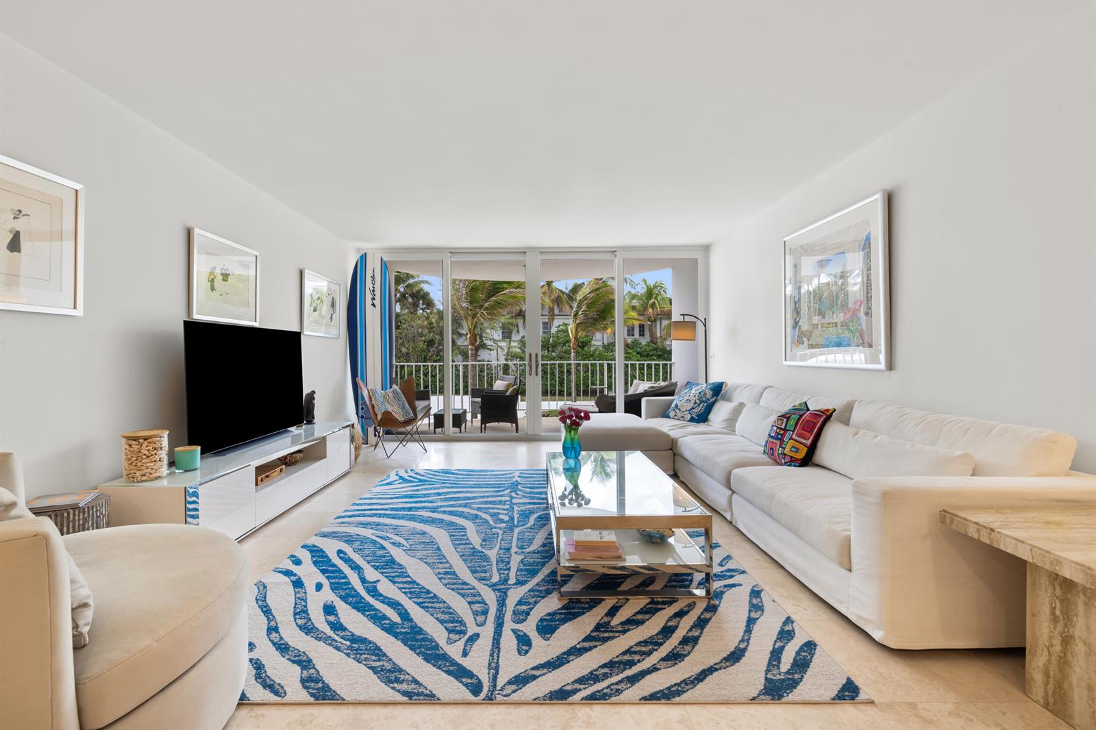 A bright living room features a white sectional sofa, a blue zebra-print rug, and balcony access — 2295 S Ocean Boulevard # 302, Palm Beach FL 33480, PALM BEACH, FL