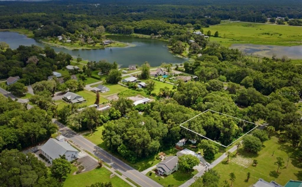 An aerial view shows a wooded residential lot outlined in white near a lake — S LAKEVIEW DRIVE, LAKE HELEN, FL